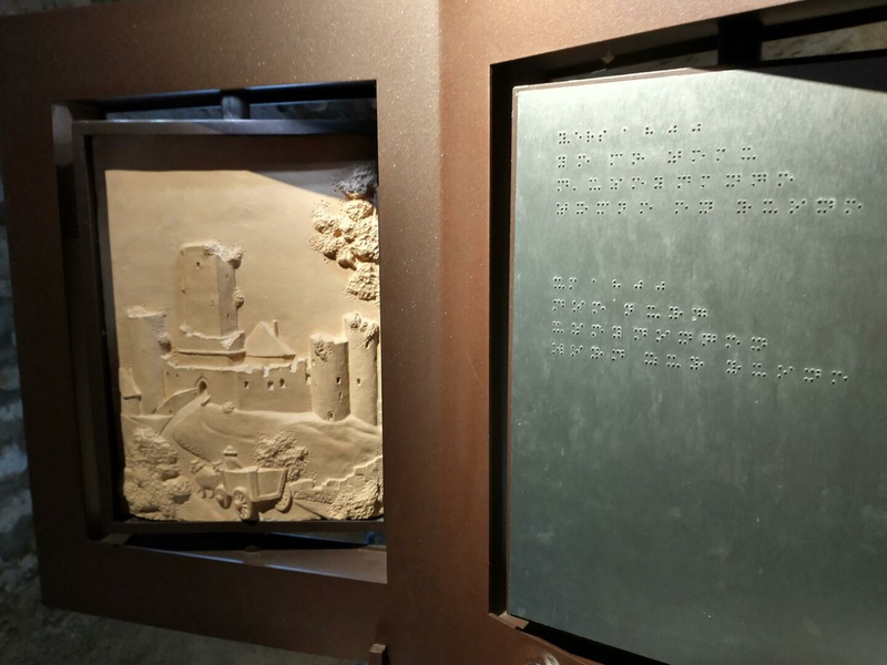 Haptische Station mit einer Reliefdarstellung einer Burg und einer dazugehörigen Brailleschrift.