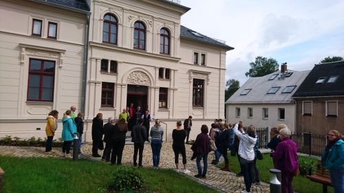 Denkmalgeschütztes Gebäude  mit einer Ansammlung von Menschen vor dem Eingang