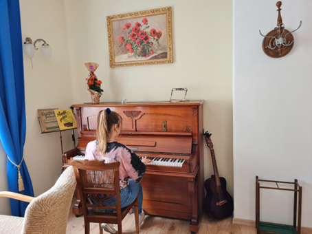 Person spielt Klavier in einer wohnlichen Atmosphäre im Café "Miteinander"