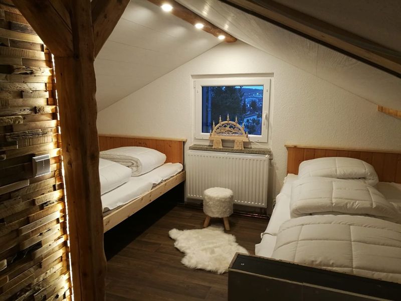 Query successful  Gemütliches Zimmer im Blockbohlenhaus mit zwei Betten und einem Schwibbogen am Fenster