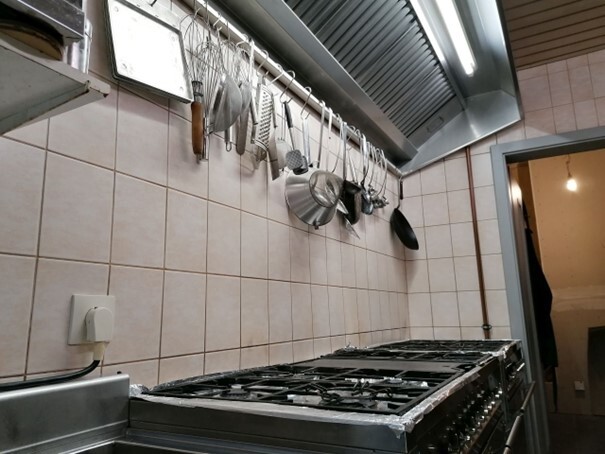 auch in den Küchenbereich wurde investiert auch in den Küchenbereich wurde investiert: Professionelle Edelstahlküche mit großem Gasherd, Dunstabzugshaube und hängenden Küchenutensilien. (Link öffnet Bild vergrößert in einem Popupfenster)