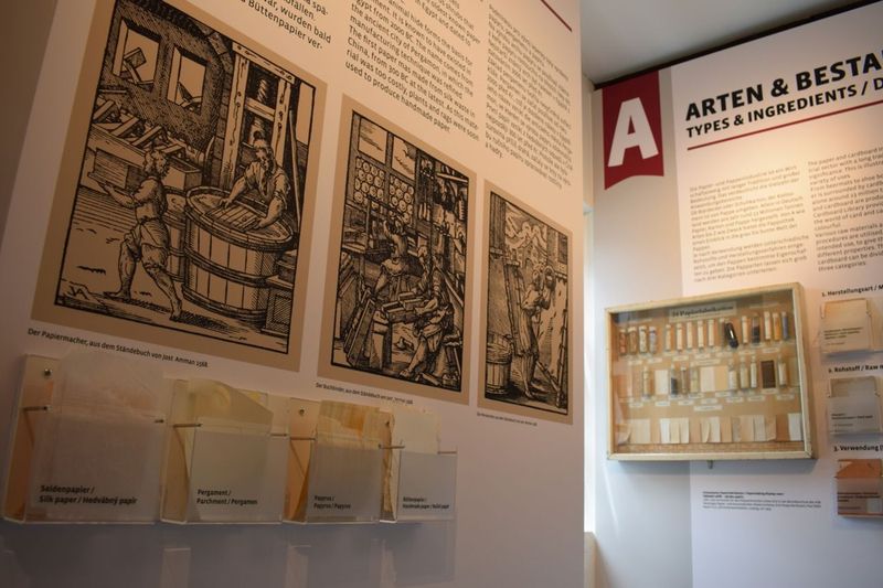 Query successful Ausstellungswand mit historischen Illustrationen zur Papierherstellung, Texttafeln und Materialproben in kleinen Fächern. (Link öffnet Bild vergrößert in einem Popupfenster).