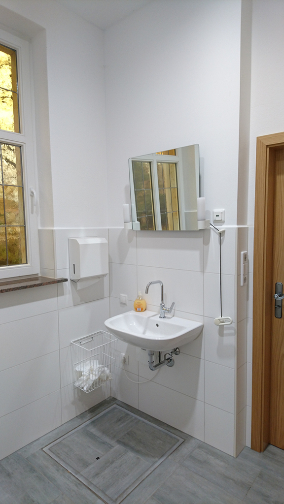 Waschbecken mit Spiegel, Handtuchspender und Fenster