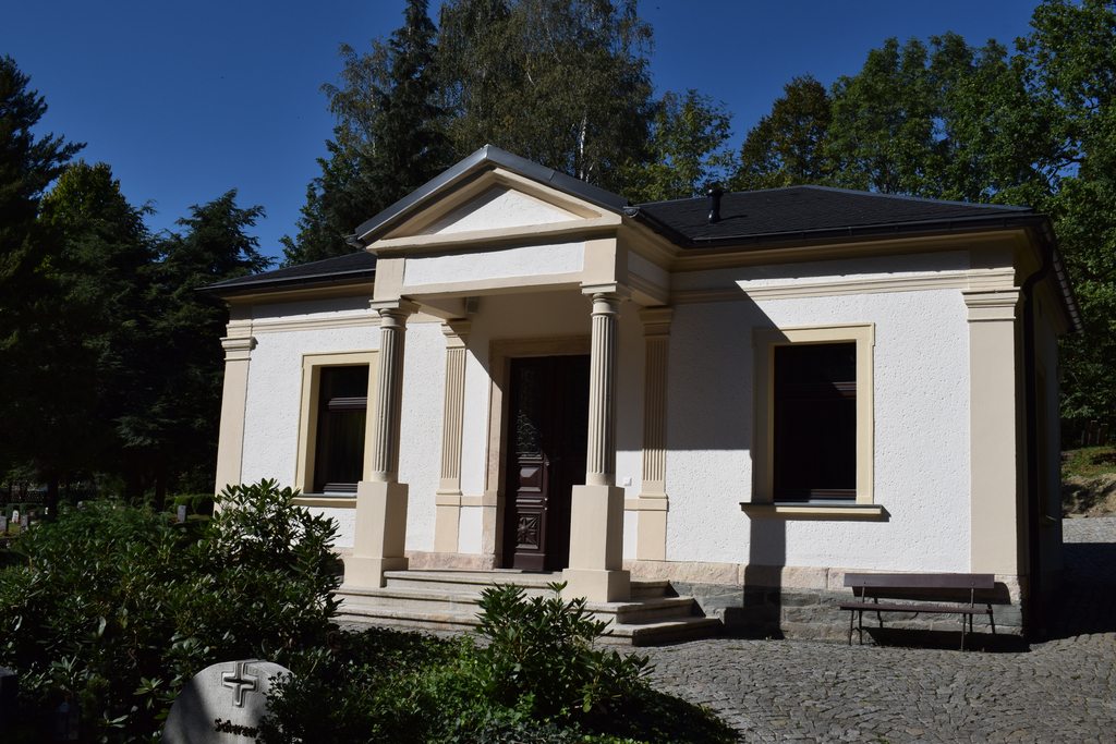 Klassizistische Totenhalle mit Säulenportal und Grabstein im Vordergrund