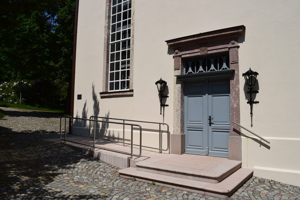 Barrierefreier Kircheneingang in Gornsdorf mit Rampe, Stufen und grauer Doppeltür